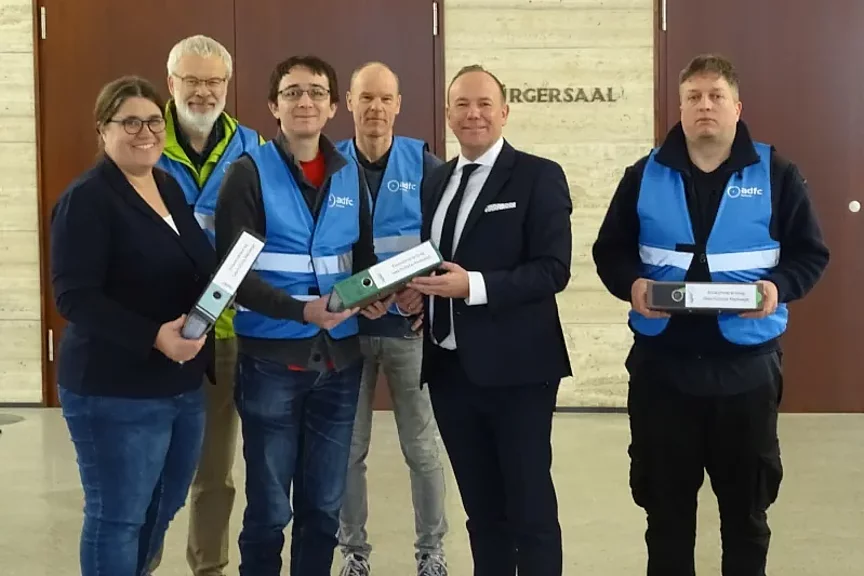 Übergabe der Unterschriften an Bürgermeister Daniel Fluhrer Das Foto zeigt mehrere Personen, die Herrn Bürgermeister Daniel Fluhrer drei Aktenordner übergeben und dabei in die Kamera schauen.